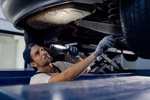 professionista effettua la manutenzione di un auto sollevata
